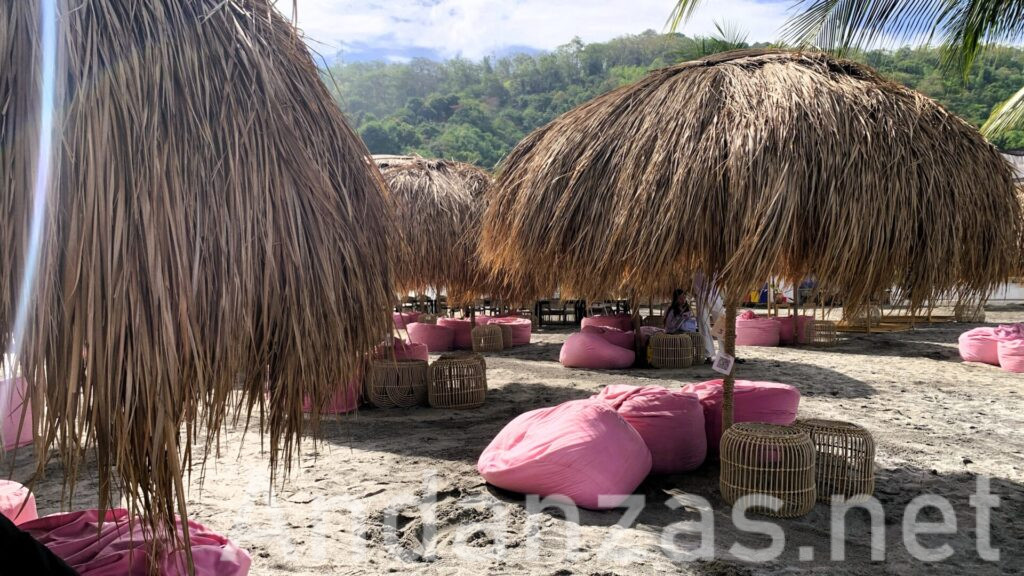 フィリピン・スービックの人気スポット、Inflatable Islandのビーチに設置されたヤシの葉の日よけとピンクの座椅子