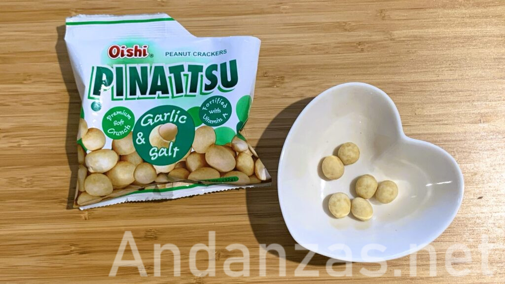 左側には白いパッケージに緑色がアクセントのPINATTSUガーリック&ソルト味、中央には実物の写真がある。右側にはハート型の小皿に6粒のPINATTSUが並べられている