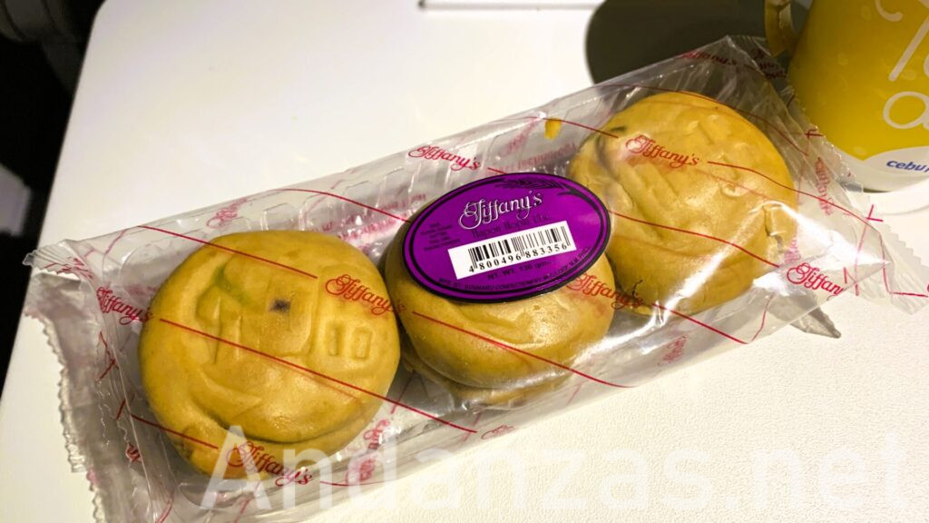 飛行機内で撮影されたフィリピンのHapon Hopia Ube。透明なパックに3つの丸い形のHopiasが並べられ、座席テーブルに置かれている