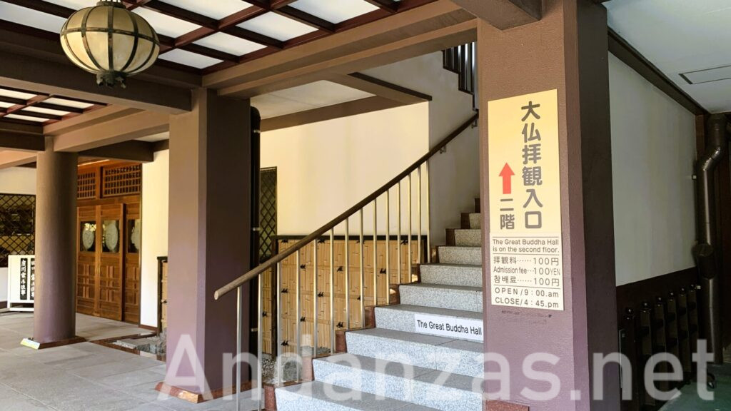 福岡・東長寺の大仏拝観入口。石造りの建物の階段には、右側の柱に「大仏拝観入口」の看板が掲げられており、階段は2階へ続いている。