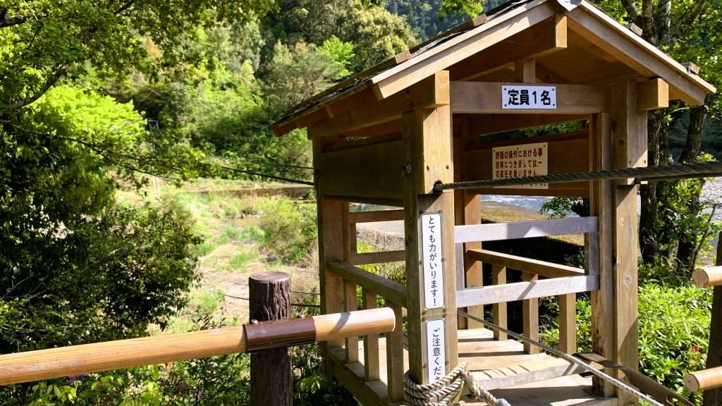 奈良県十津川温泉のホテル昴の野猿を撮影。木製で屋根付きの人力ロープウェイ型アクティビティ。ロープを引いて川を渡る仕組みで、定員一名やとても力がいりますなどの注意書きが貼られた十津川村の名物風景。