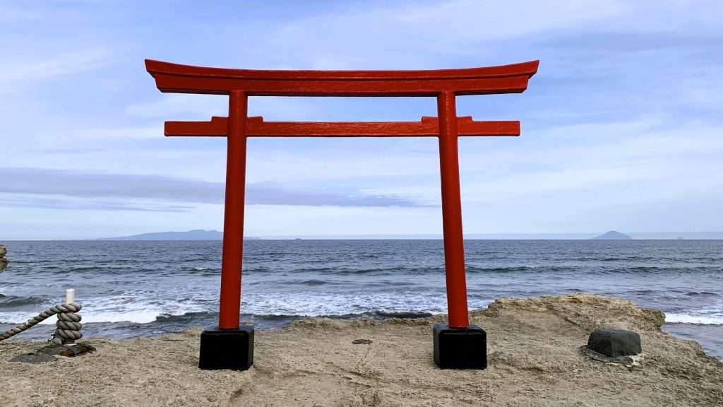 静岡県下田市・白浜海岸の伊古奈比咩命神社(白濱神社)の海沿いの鳥居を撮影。岩上に立つ朱色の鳥居と、その奥に広がる海や遠くの島々が美しく調和した絶景。晴れた空の下で見る、静岡県伊豆半島の歴史あるパワースポットの風景。